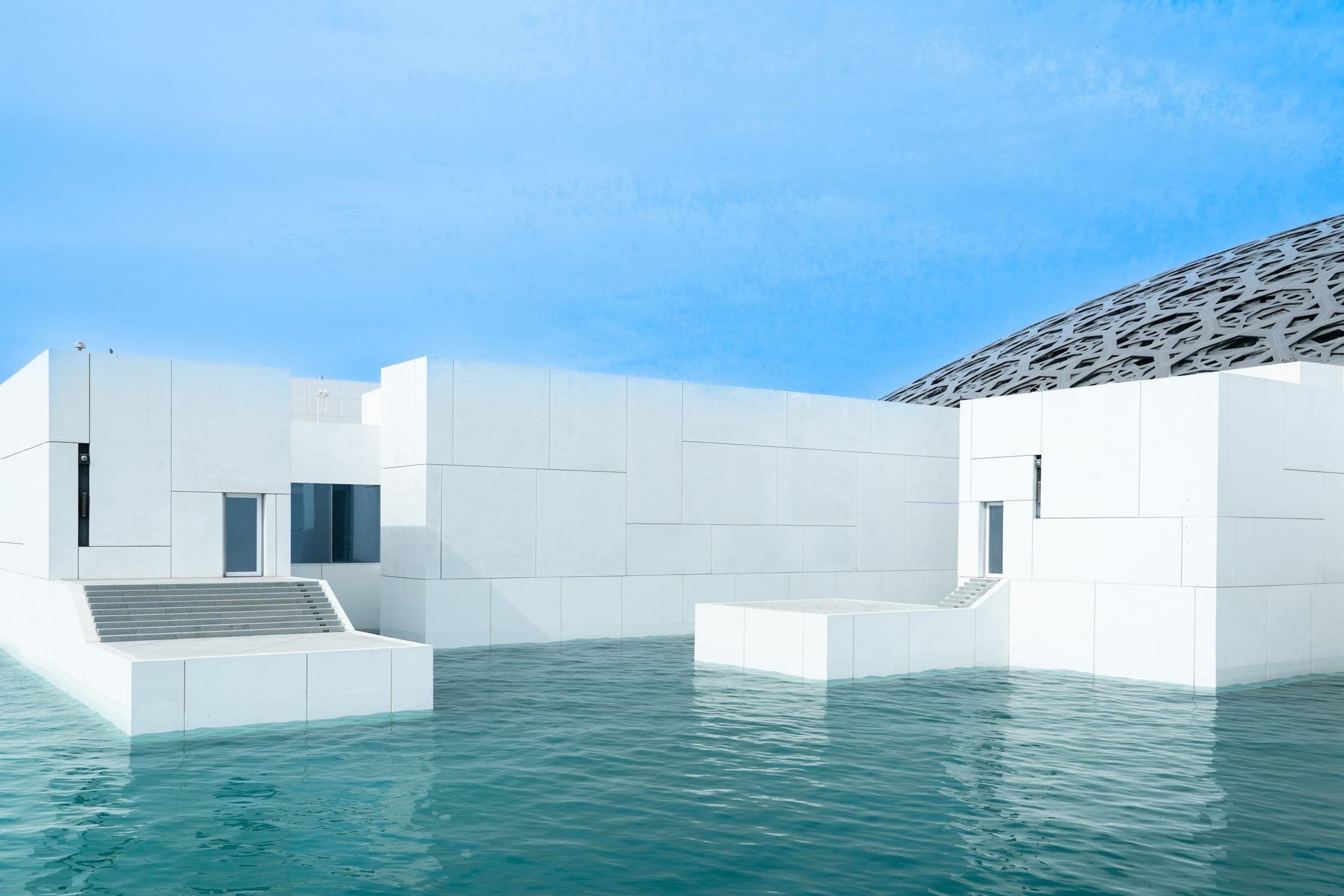 White architecture of Louvre Abu Dhabi beside the water